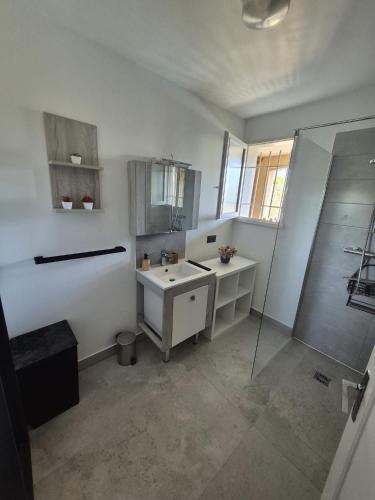 a white bathroom with a sink and a shower at La Verdière in Barjols