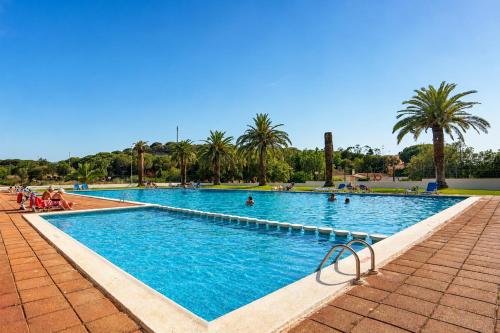 a large swimming pool with palm trees and people in it at Kampaoh Palamós Internacional in Palamós