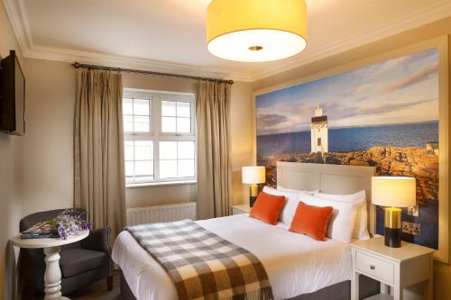 a bedroom with a bed with a lighthouse painting on the wall at The Wild Atlantic Lodge in Ballyvaughan