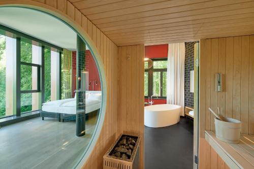 a bathroom with a mirror and a tub and a bedroom at Studios & Spa Suites Rigiblick in Zurich
