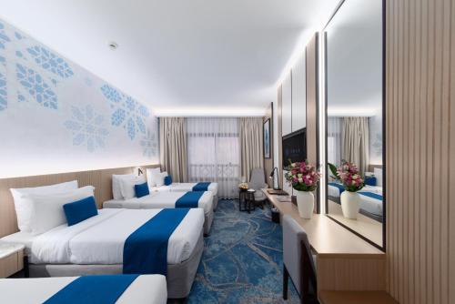 a hotel room with three beds and a desk at Jiwar Al Madina Hotel in Medina