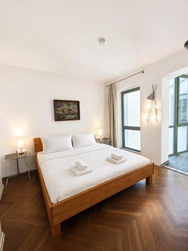 a white bedroom with a large bed with white sheets at Apartmenthaus Albrechtsburg in Bad Schandau