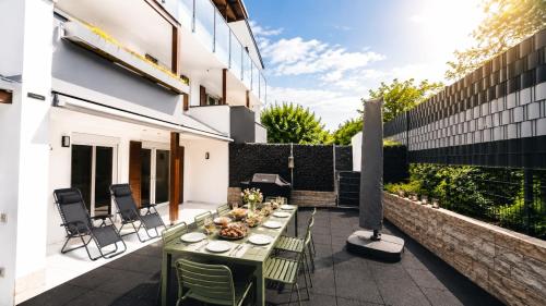 a patio with a table and chairs on a building at Berg Fux - Zwei Ferienhäuser mit je 5 und 6 Schlafzimmern mit eigener Dachterrasse - fantastischem Bergblick - Weber Gas Grill in Sonthofen