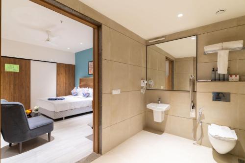 a bathroom with a sink and a toilet and a bed at Lords Inn Sanand in Chharodi
