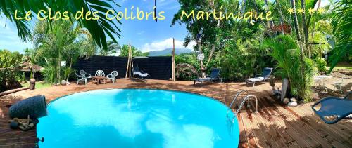 a swimming pool in a yard with chairs and a table at LODGE PAMPLEMOUSSE avec PISCINE privative , dans parc calme à 500 m plage in Le Carbet