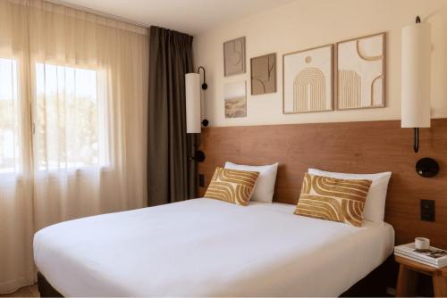 a bedroom with a large white bed and a window at Hôtel Golf Fontcaude in Montpellier
