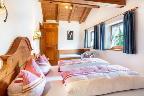 two beds in a bedroom with blue curtains at Weibhauser Franzl in Ruhpolding