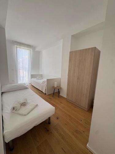 ein weißes Schlafzimmer mit zwei Betten und Holzboden in der Unterkunft Dimora Caprera - Appartamenti in Falconara Marittima
