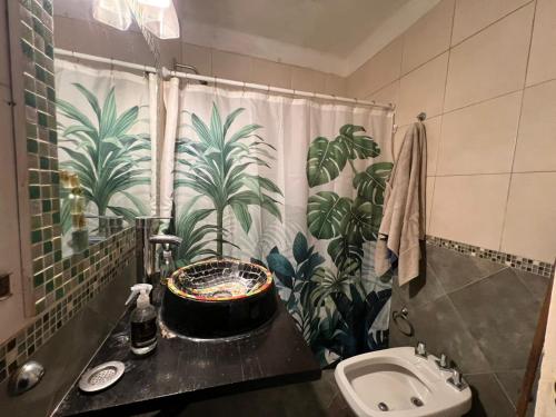 a bathroom with a sink and a shower curtain with plants at Casa Olivos in Olivos
