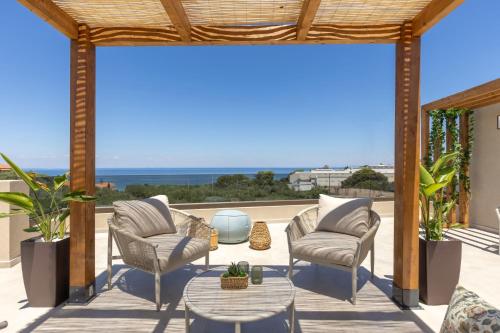 a patio with chairs and a table and a view of the ocean at Ark Luxury Suite, Hot tub & Sea Views, by ZanteWize in Tragaki