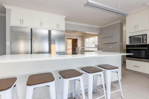 a kitchen with a white counter and stools at Vallen Lodge 2 in Ballito