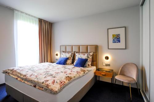 a bedroom with a bed and a chair and a window at Victory port Apartmán in Liptovský Mikuláš