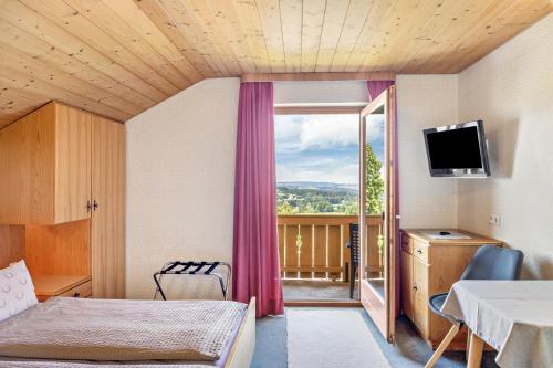 a room with a bed and a balcony with a television at Ferienwohnung Panorama Bad Kohlgrub in Bad Kohlgrub