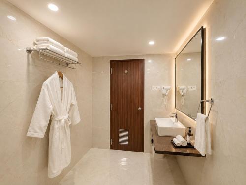 a white bathroom with a sink and a mirror at Hotel Prabhu Pada Puri - Beach Front Hotel With Swimming Pool And Restaurant - SPA- Banquet - Parking Facility in Puri