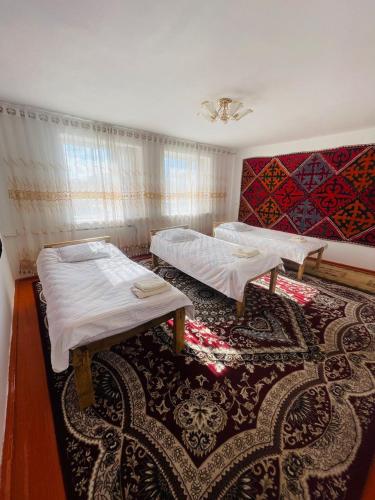 a room with two beds and a rug at Guest house Kyial in Naryn