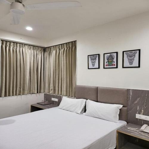 a bedroom with a large white bed in front of a window at Hotel Jay Palace Inn in Solapur