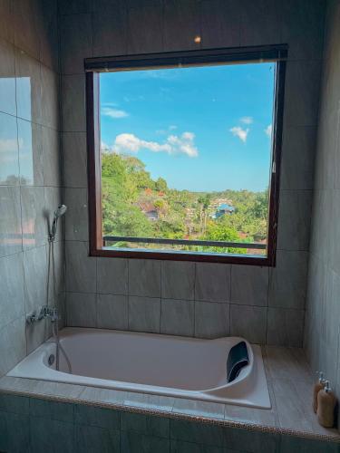 a bath tub in a bathroom with a window at Heri house ubud in Ubud