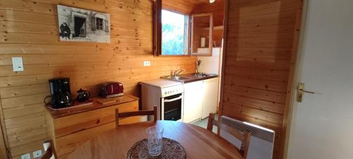 a wooden kitchen with a table and a sink at Chalet rocenel in Le Malzieu-Ville