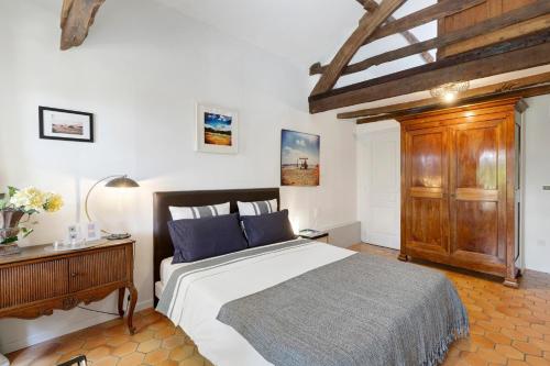 a bedroom with a large bed and a wooden cabinet at Les Temps Des Sources in Veyrines-de-Domme