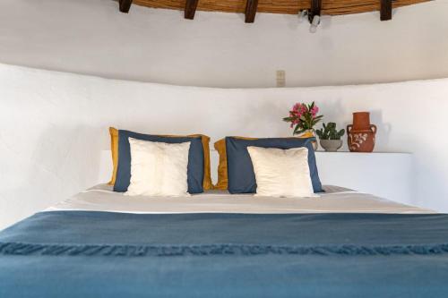 a bed with blue and white pillows on it at The Windmill Serifos in Serifos Chora