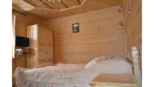 a bedroom with a bed in a wooden wall at Садиба Хатинка у Люби in Yaremche