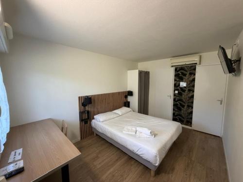 a bedroom with a white bed and a wooden table at Couett' Hotel Rumilly in Rumilly