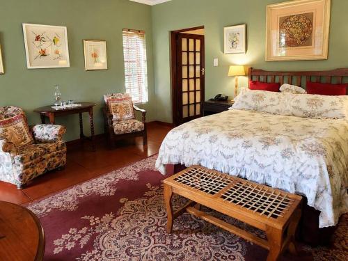 a bedroom with a bed and a table and a chair at Quiet Mountain Country House in Hekpoort