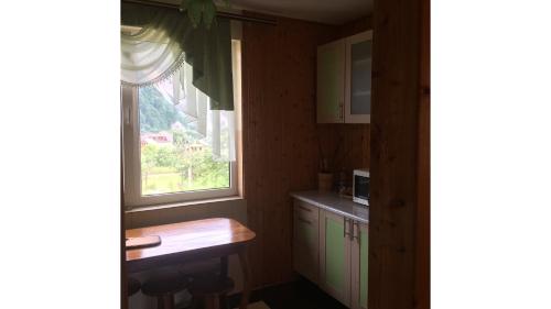 a kitchen with a window and a table in it at Садиба Хатинка у Люби in Yaremche