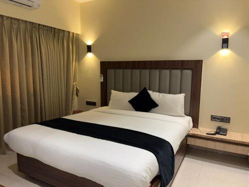 a bedroom with a large bed with white sheets and pillows at Hotel Golden Crown in Mumbai