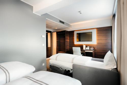 a hotel room with three beds and a television at Premier Inn Berlin City Süd in Berlin