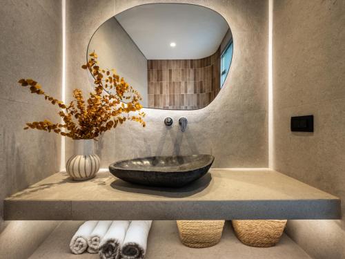a bathroom with a stone sink and a mirror at Natalie Hotel in Laganas