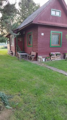 a red house with a porch and a yard at Chatka in Partizánska ľupča