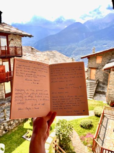 a person holding a book in front of a mountain at Maison Arcade in La Salle