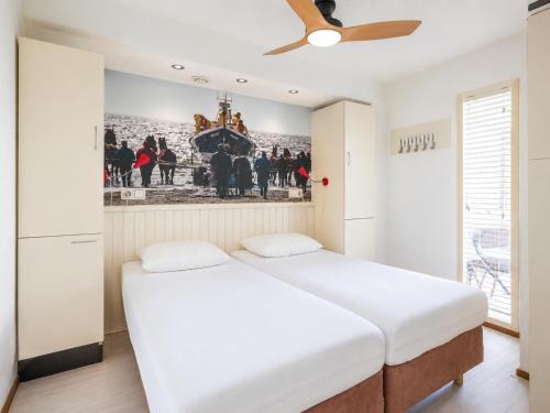 a bedroom with two beds and a ceiling fan at Appartement De Noordkaap in Hollum