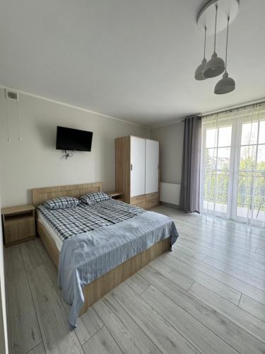 a bedroom with a bed and a flat screen tv at Willa Relaksowa in Karwia