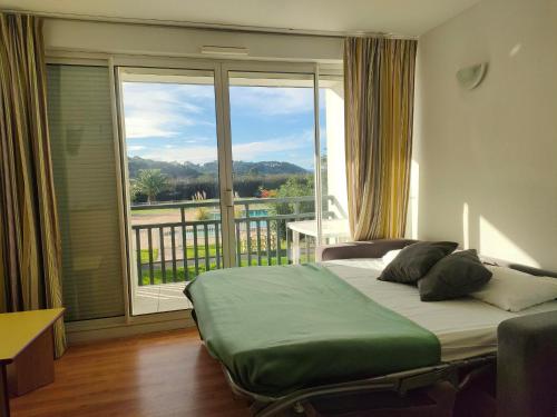 a bedroom with a bed and a large window at Résidence Mer & Golf Ilbarritz in Bidart