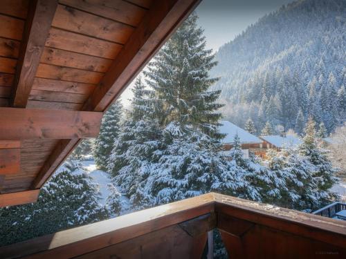 a view from the balcony of a cabin with snow covered trees at Chalet Igel - OVO Network in Châtel