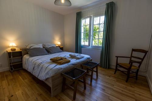 a bedroom with a bed with two chairs and a window at Gîte du mouta in Saint-Justin