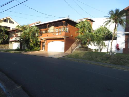 a brown house with a gate and a garage at Cariari Bed & Breakfast in San José
