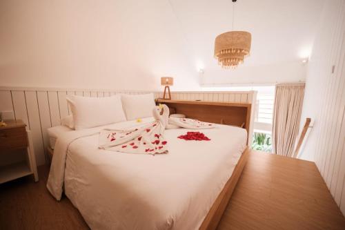 a bedroom with a white bed with red flowers on it at Santai Studios in Badung
