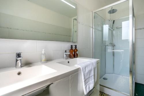 a white bathroom with a sink and a shower at La parenthèse Océane -Avec piscine in Concarneau