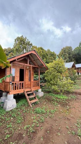 a wooden cabin with a porch in a field at Kuna GlampCamp in Gitgit