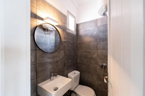 a bathroom with a toilet and a mirror and a sink at Nalo Suites & Villas in Kithnos