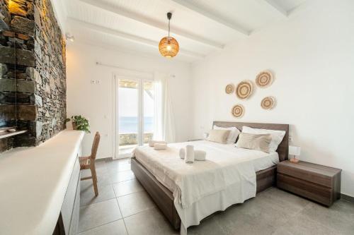 a white bedroom with a bed and a large window at Nalo Suites & Villas in Kithnos
