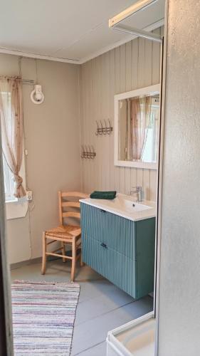 a bathroom with a sink and a mirror and a chair at Romantic farmhouse in Vaksdal