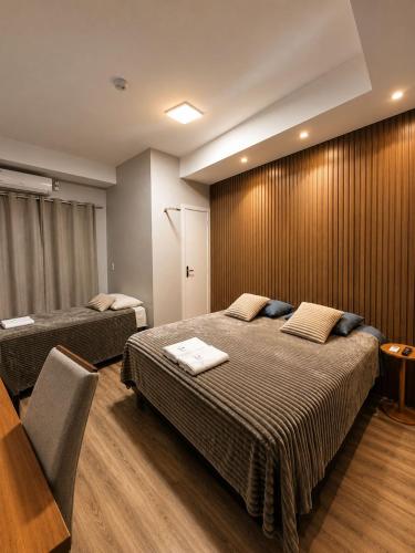 a hotel room with two beds and a table and chairs at Hotelcity in Brusque