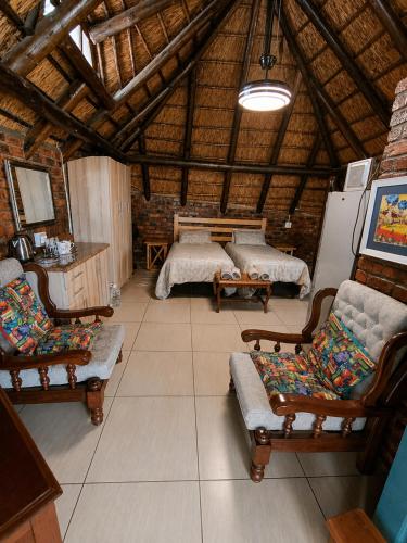 a room with two beds and chairs in a building at WHY NOT GUESTHOUSE in Bothaville