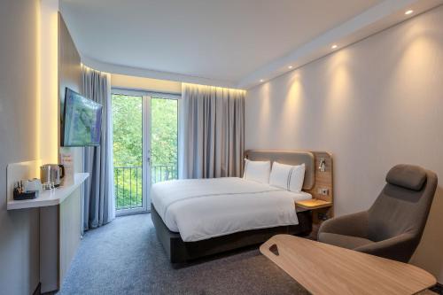 a hotel room with a bed and a chair at Premier Inn Göttingen in Göttingen