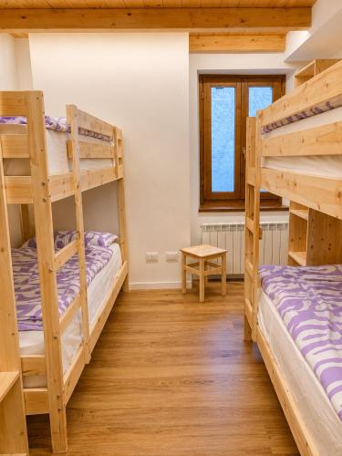 two bunk beds in a room with wooden floors at Clelia appartamento 6 posti vicino le piste da sci in Temù