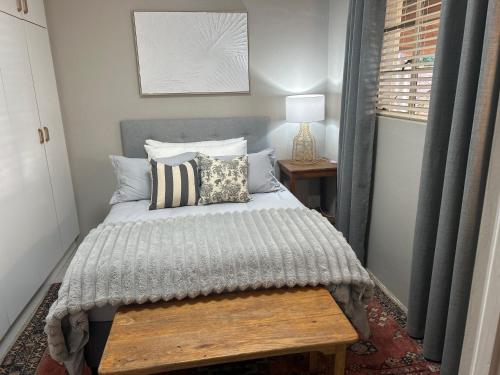 a bedroom with a bed with a wooden bench next to a window at Mariri Farm Cottage in Patentie
